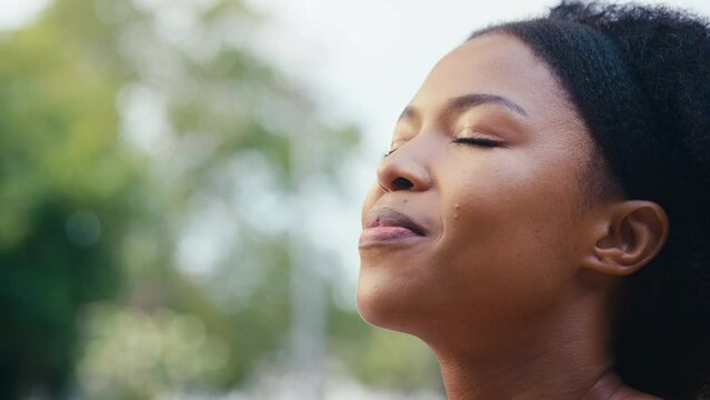 Portrait smiling woman standing outdoors closing eyes and breathing deeply in countryside or garden - shot in slow motion