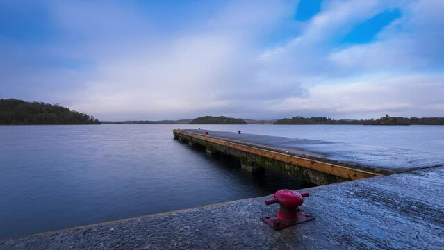 Time lapse of a concrete lake pier with forest in distance on a cloudy sunny day at Lough Key in county Roscommon in Ireland.