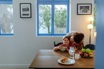 Mother kissing her daughter during breakfast