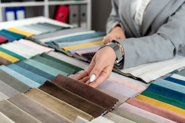 female hand selects the color fabric catalog she likes for new sofa