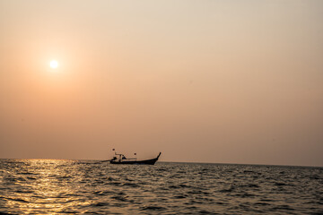 drewniana łódka na tle zachodzącego słońca