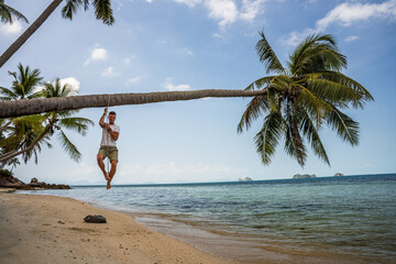 Mężczyzna na rajskiej plaży wisi na palmie