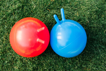 childhood, leisure and toys concept - two bouncing balls or hoppers on grass - 767711049
