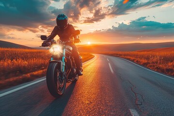 A man is riding a motorcycle down a road at sunset. The sky is filled with clouds, and the sun is setting in the distance