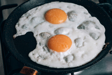 Frying egg in a cooking pan in the domestic kitchen.