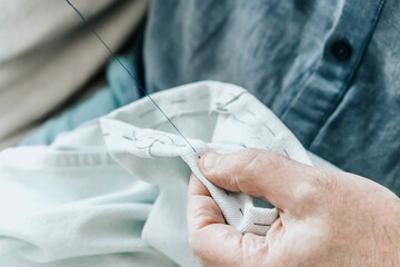A man sews jeans with his hands. Close-up.