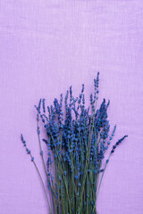 View from above of beautiful fragrant bouquet of french lavender on purple fabric background. Vertical image