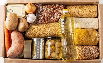 food storage, donation and eating concept - close up of box with groceries and preserves on white...