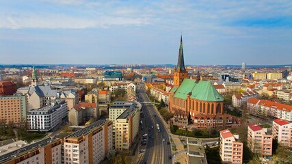 Drone photo captures Kardynała Stefana Wyszyńskiego Street in Szczecin, Poland, with the Basilica of St. James the Apostle and city skyline on a March day. 