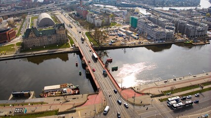 Drone shot captures March day in Szczecin, Poland, showing Long Bridge with passing cars.