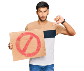 Young handsome man holding prohibited warning banner with angry face, negative sign showing dislike with thumbs down, rejection concept