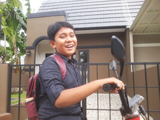 an elementary age school boy with his bag pack in front of the house use electric bicycle ready go to school