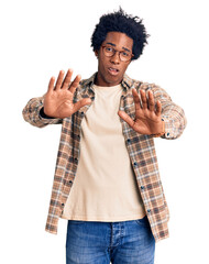 Handsome african american man with afro hair wearing casual clothes and glasses moving away hands...