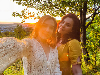 two pretty women take a selfie at sunset