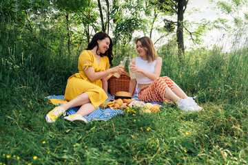 a couple of women on a blue blanket outdoors on a picnic