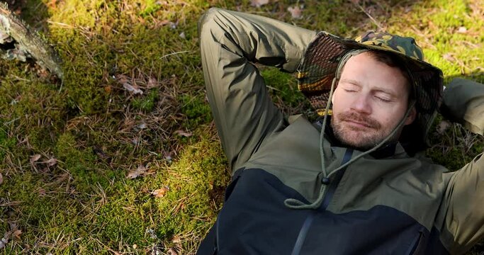man sleeping and resting on green forest moss. enjoying beauty and tranquility of nature