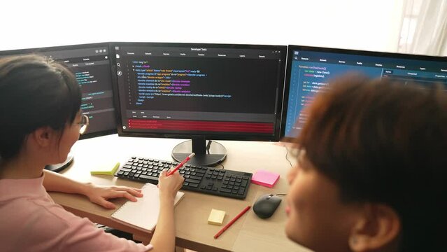 Slow motion back end software developer engineer for computer programming working together on debugging writing computing code, solving complex algorithms display on monitor in office. Burgeoning