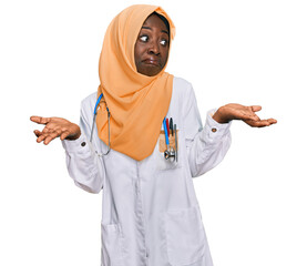 Beautiful african young woman wearing doctor uniform and hijab clueless and confused expression...