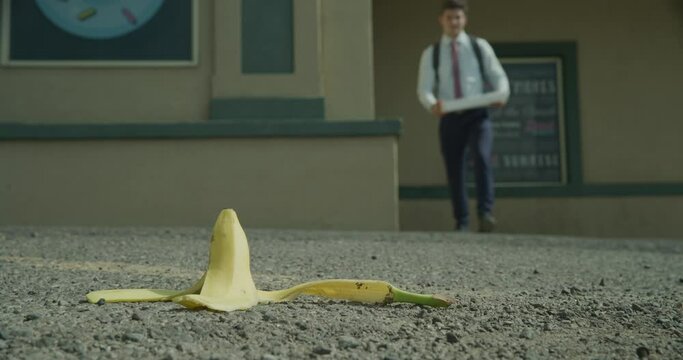 Business man with box slipping on banana peel - low, close up