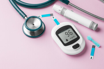 Blood glucose meter, lancet and stethoscope on pink background, diabetes concept