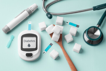 Diabetes concept with blood glucose meter and sugar cube on spoon on green background