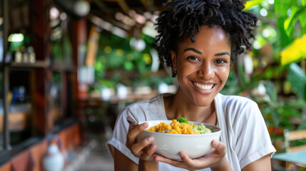 Cheerful woman standing and holding a bowl of food in her hands - obrazy, fototapety, plakaty