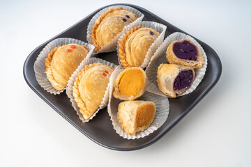 Curry puffs purple and sweet potatoe on black plate on white background, Curry puff pastry on white background.