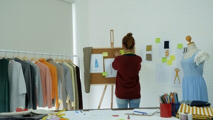 Entrepreneur fashion designer in textile business designing new retail clothing collection. Happy working woman seamstress, designer working on fabric sketches. Young designer fashion concept