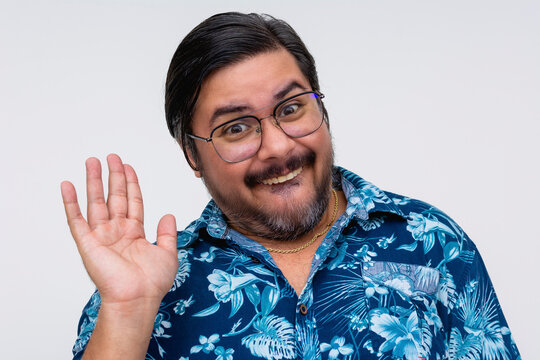 A cheerful, nerdy man wearing glasses and a Hawaiian shirt appears slightly embarrassed as he gives an awkward wave.