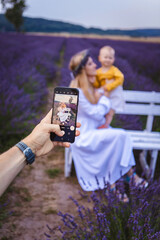 A man takes a picture of his wife and child on his phone