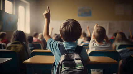 Little boy raises his hand to answer a question in the classroom - obrazy, fototapety, plakaty