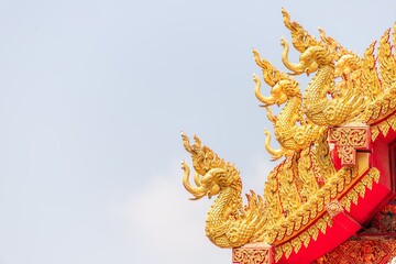 Golden Naga Serpents on Traditional Temple Roof Against Blue Sky