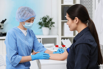 Laboratory testing. Doctor taking blood sample from patient at white table in hospital