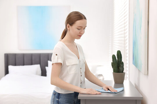 Woman with microfiber cloth cleaning grey chest of drawers in room