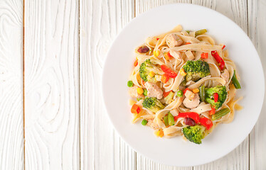 Pasta with vegetables on a plate against a brick wall background