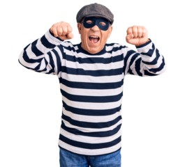 Senior handsome man wearing burglar mask and t-shirt angry and mad raising fists frustrated and furious while shouting with anger. rage and aggressive concept.