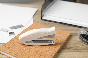Stapler, notebook and papers on wooden table