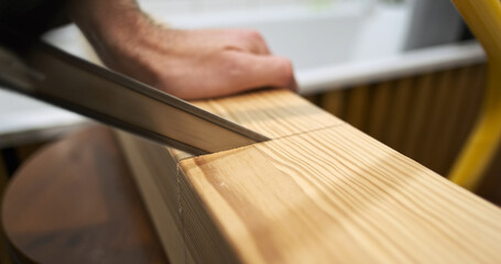 Start hand saw saws, begin thick square wooden beam, side view, close-up, indoors. Concept of home craftsman, hobby, woodworking.
