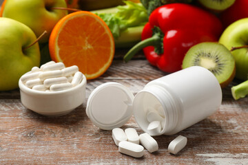 Dietary supplements. Overturned bottle, pills and food products on wooden table, closeup