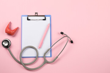 Endocrinology. Stethoscope, clipboard, model of thyroid gland and pen on pink background, flat lay....