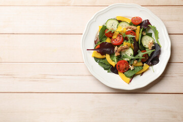 Tasty fresh vegetarian salad on light wooden table, top view. Space for text