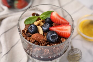 Tasty granola with berries and nuts in glass on table, closeup