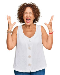 Beautiful middle age mature woman wearing casual white shirt celebrating mad and crazy for success...
