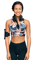 Beautiful hispanic woman wearing sportswear and headphones with a happy and cool smile on face....