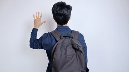 Back view of a young Asian male student carrying a bag