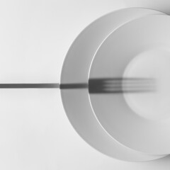 Detalle minimalista de platos listos para comer. Juego de líneas y sombras (un tenedor) con fondo...