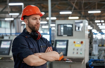 Confident facial expression. Factory worker is indoors with hard hat