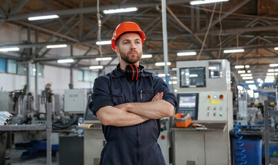 Confident facial expression. Factory worker is indoors with hard hat