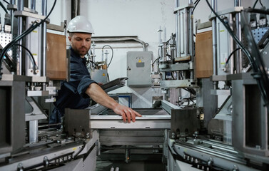 Checking quality of material, control. Factory worker is indoors with hard hat