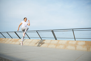 Young woman runner jogger exercising outdoors, running jugging on the city bridge. Female athlete...